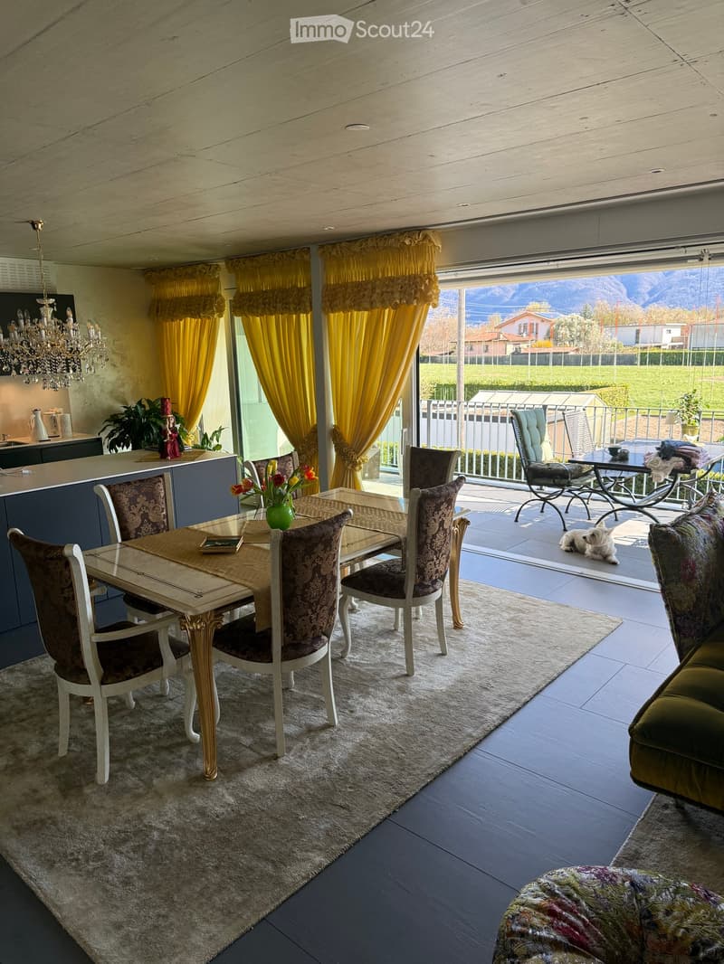 Dining area with a table and chairs, carpet, chandelier, yellow curtains, balcony with a table and chairs, and a view of the mountains