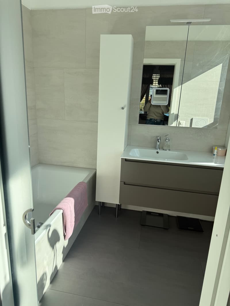 Bathroom with bathtub, sink, mirror, and cabinet