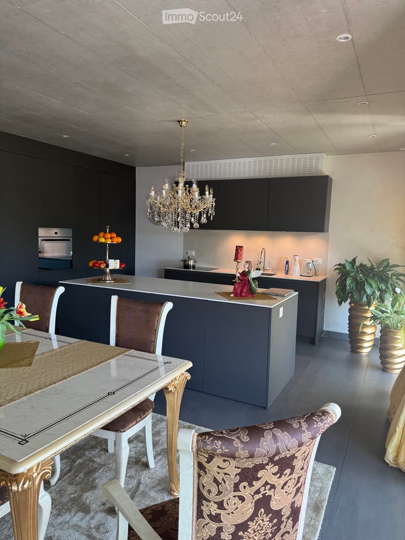 modern kitchen with island, chandelier, black cabinets, marble countertop, dining table, chairs, carpet, plants