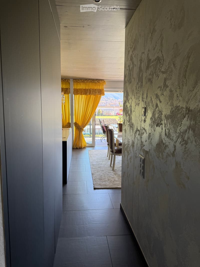 Corridor with black tiles, yellow curtains, dining area with chairs and table, balcony with view
