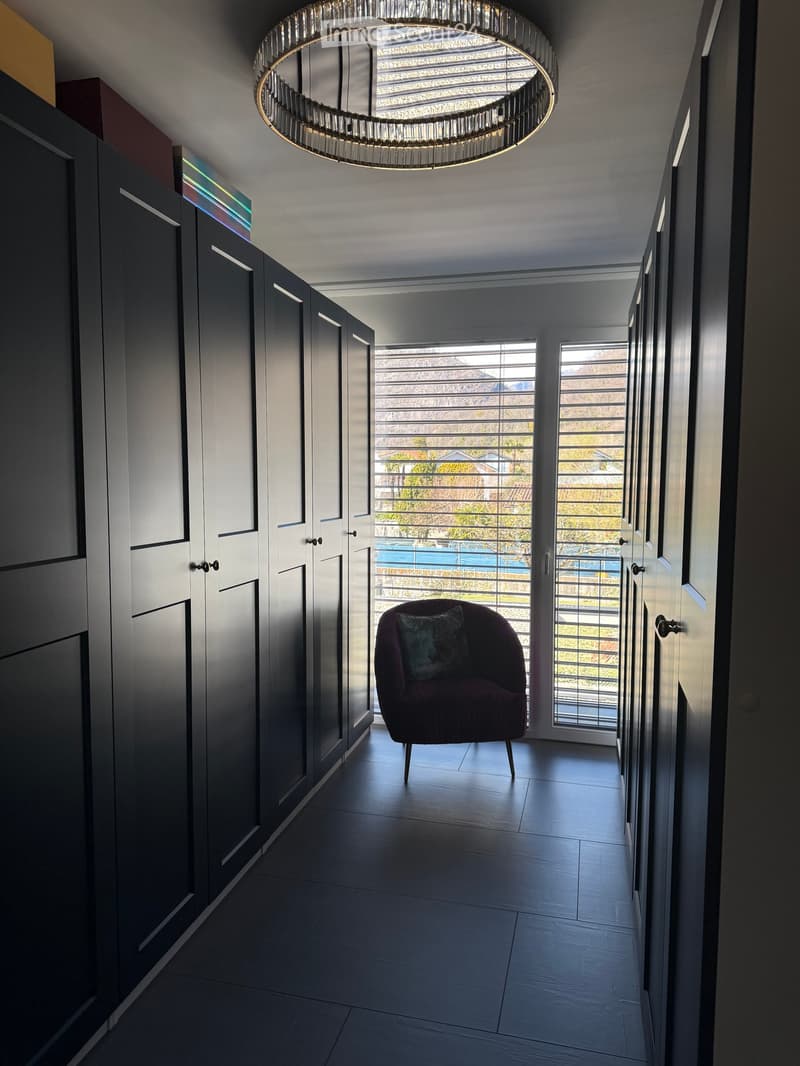 walk-in closet with built-in cabinets, a chair, and a window with a view of the outside