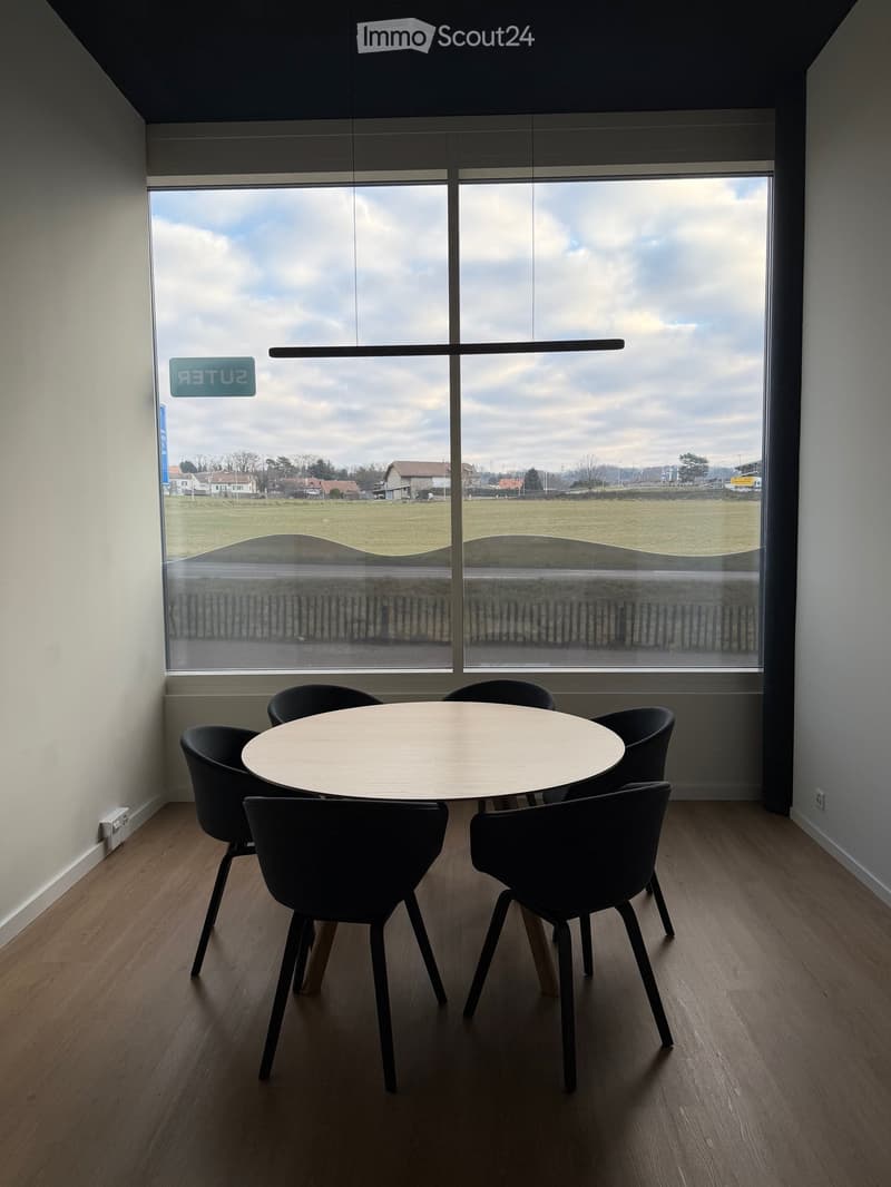 Wooden flooring, round wooden table, black chairs, large window with scenic view