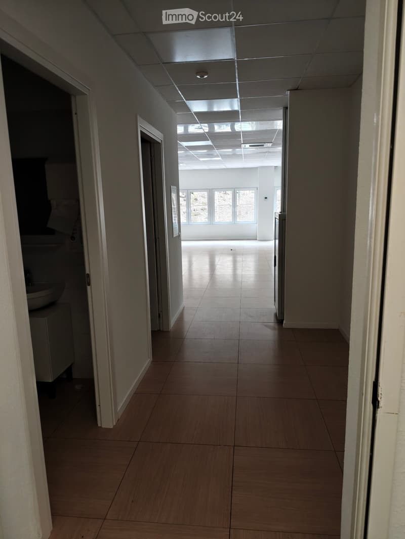 Empty hallway with tiled floor, white walls, and ceiling lights