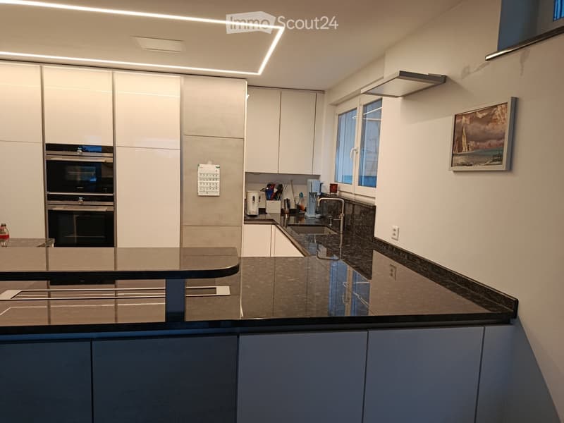 modern kitchen with white cabinets, black granite countertops, built-in oven, dishwasher, sink, faucet, and a picture frame on the wall