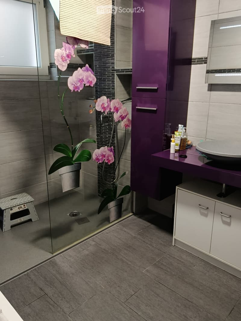 modern bathroom with glass shower, purple cabinets, white sink, orchids on glass