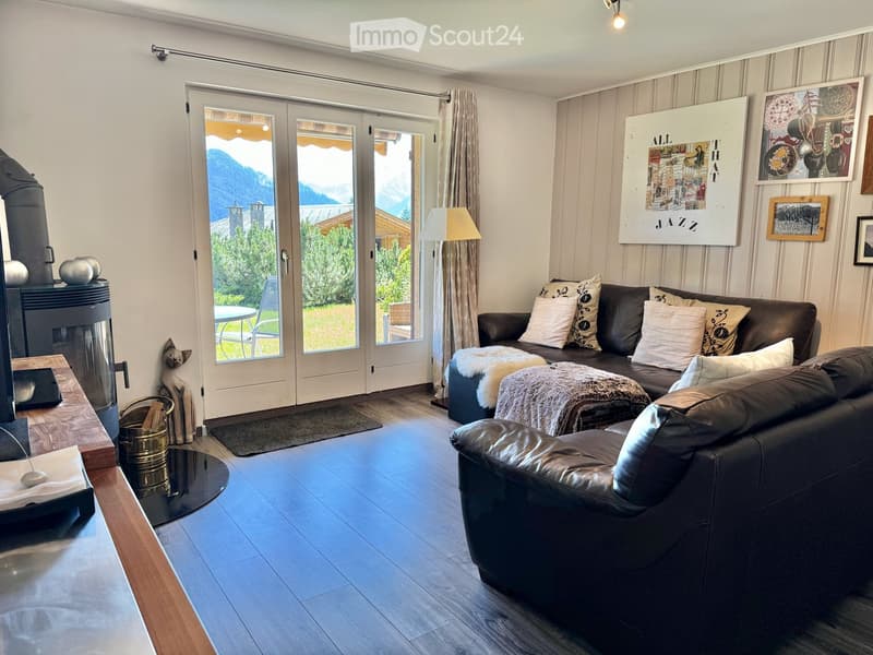 modern living room with black leather sofa, glass doors, wooden floor, fireplace, large windows, view of mountains