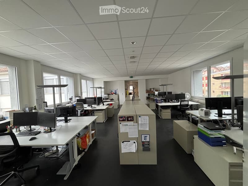 modern office space with white walls, black floors, multiple desks, computer monitors, chairs, cabinets, and lamps