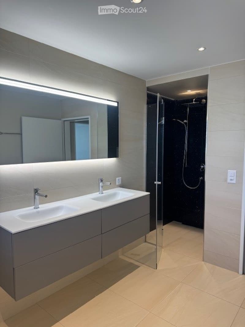 modern bathroom with double sink, large mirror, shower, and tiled floor