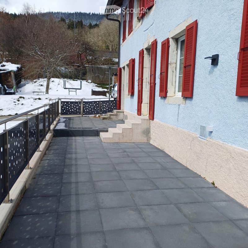 Blue house with red shutters, tiled terrace, metal railings, snow on the ground