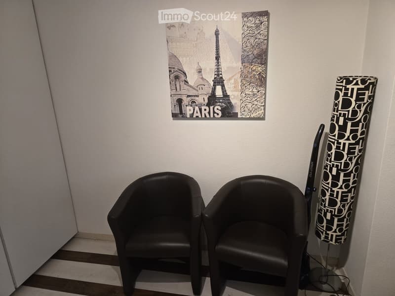 small room with two black leather chairs, a Paris poster, and a lamp