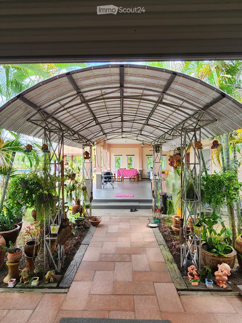 covered walkway, brick floor, metal frame, plants, trees, pink table, chairs, pink cloth