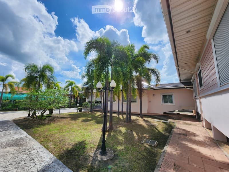 Palm trees, brick pathway, lamp post, grassy area, house in the background