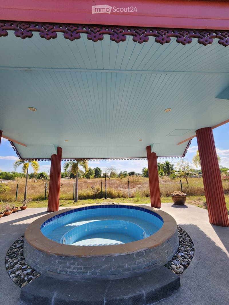 Outdoor area with a swimming pool under a gazebo with red pillars and a white ceiling