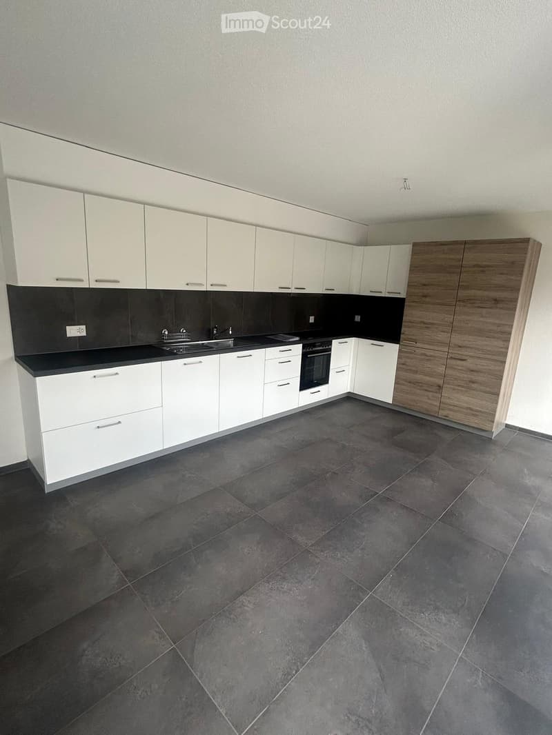 modern kitchen with white cabinets, black countertops, stainless steel sink, oven, dishwasher, tiled floor
