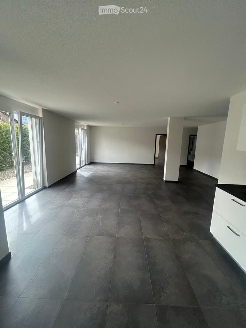 large open space, white walls, black tiled floor, sliding glass doors, white cabinets