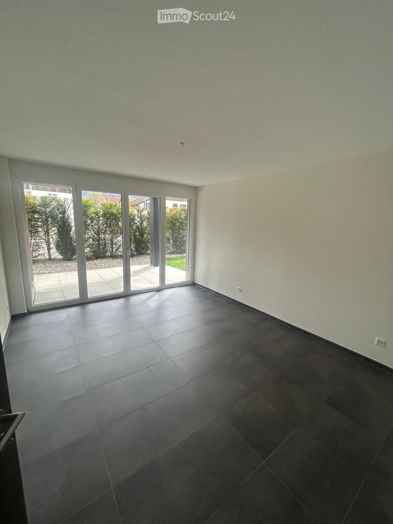 empty room, large sliding glass doors, black tiled floor, white walls, power outlet