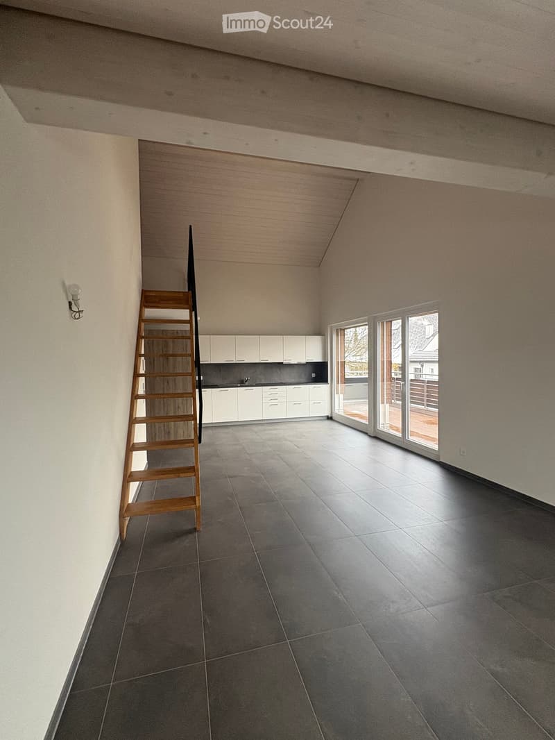 Empty room, wooden staircase, white walls, tiled floor, kitchen with white cabinets, sliding glass doors, balcony