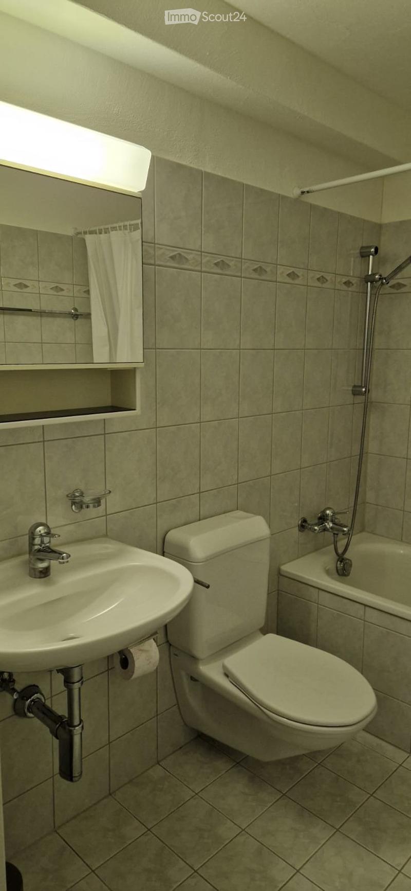 Bathroom with white sink, toilet, bathtub, and shower. Tiled walls and floor.