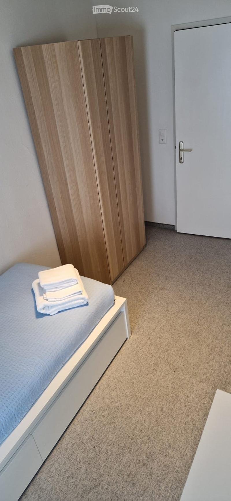 Single bed, wooden wardrobe, white door, white bedsheet, white towels