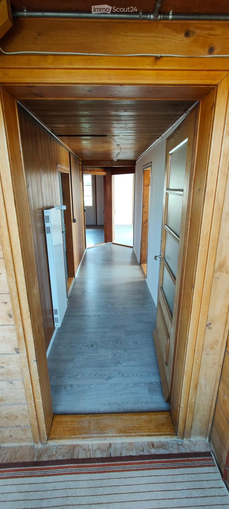 long hallway, wooden walls, white radiator, gray floor, doors on both sides