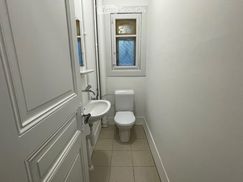 small bathroom with toilet, sink, and window