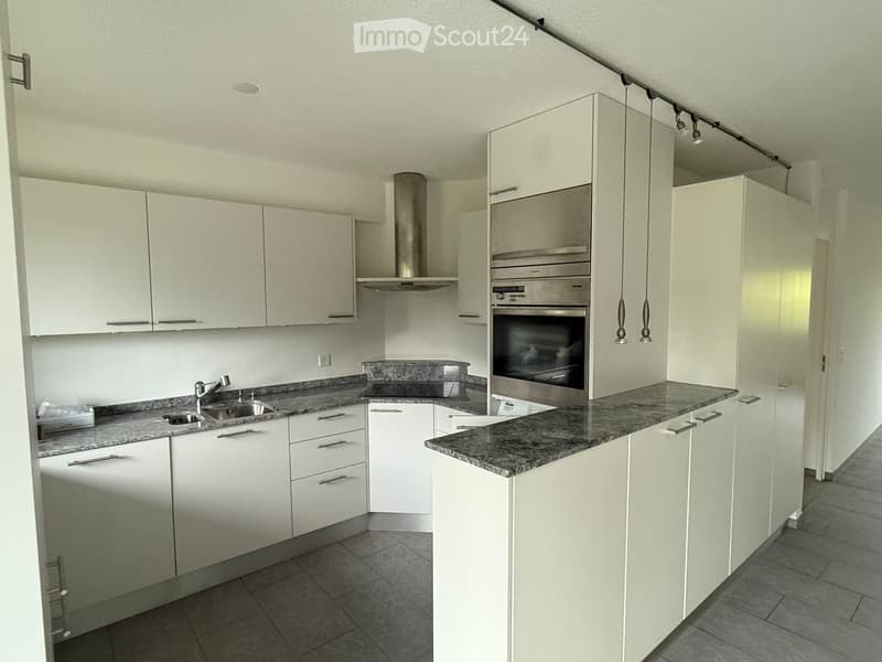 modern kitchen with white cabinets, granite countertops, stainless steel appliances, under-cabinet lighting, and a sink with a faucet