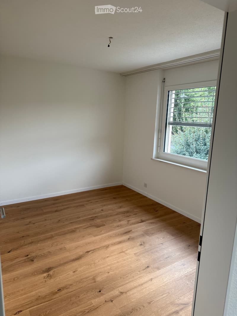 empty room, wooden floor, white walls, window with blinds, power outlet