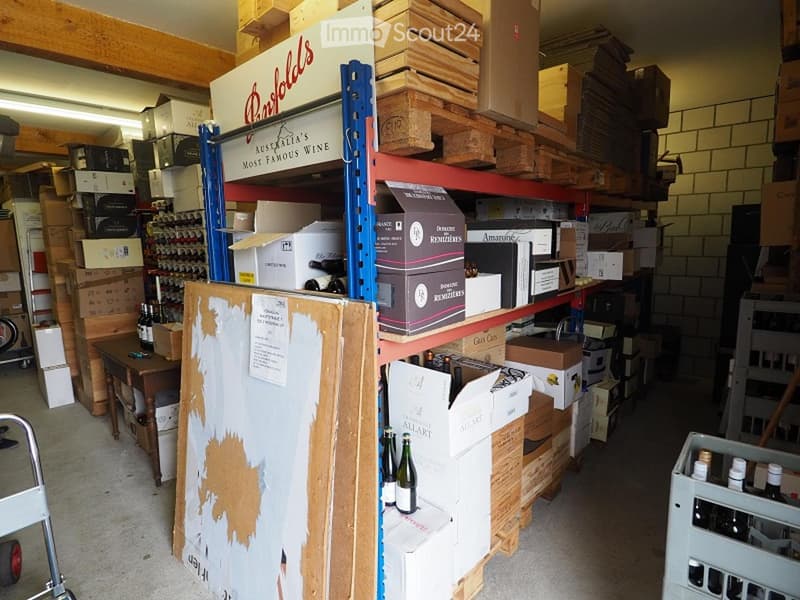 Storage room with wooden pallets, boxes, wine bottles, and a trolley