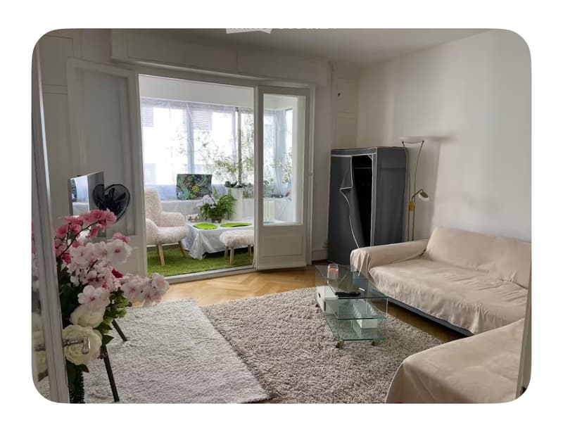living room with white walls, wooden floor, glass doors leading to a balcony, beige sofa, glass coffee table, white rug, white armchairs, white table, green plants, white curtains