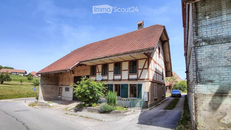 2 story house, red roof, wooden and brick walls, green shutters, small garden, car parked in front