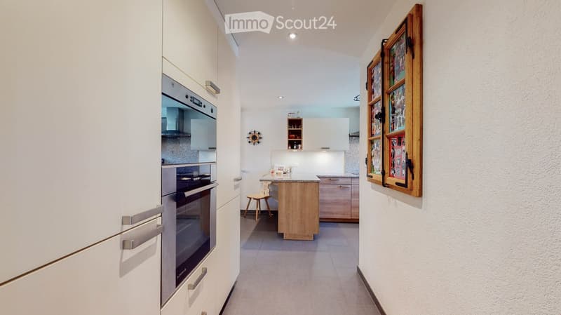 modern kitchen with white cabinets, granite countertop, stainless steel appliances, wooden chair, wooden frame on wall