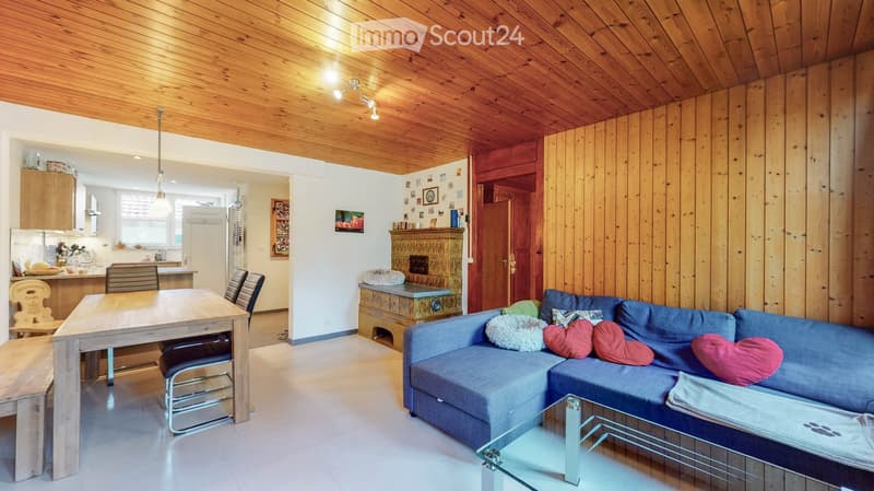 living room with wooden ceiling, fireplace, blue sofa, wooden table, chairs, wooden bench, kitchen area