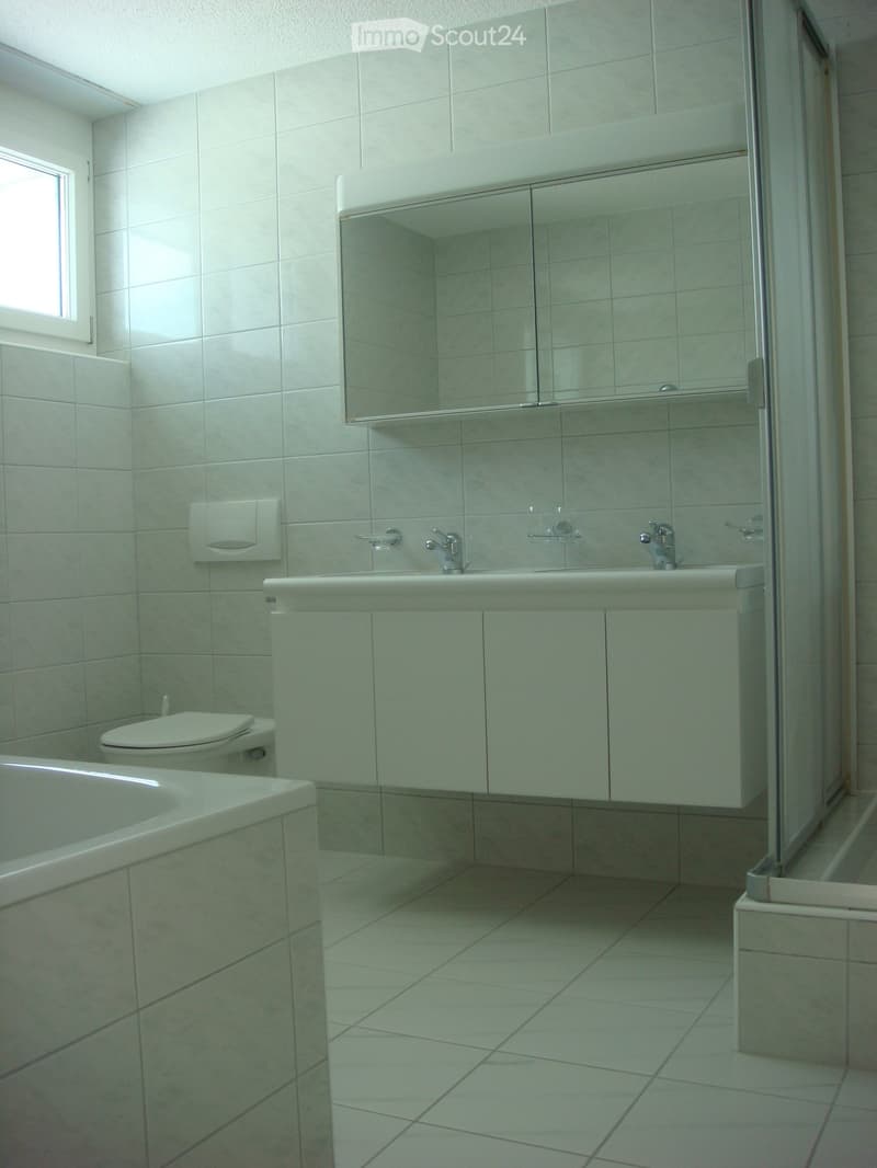 modern bathroom with white tiles, bathtub, toilet, double sink, mirror, shower