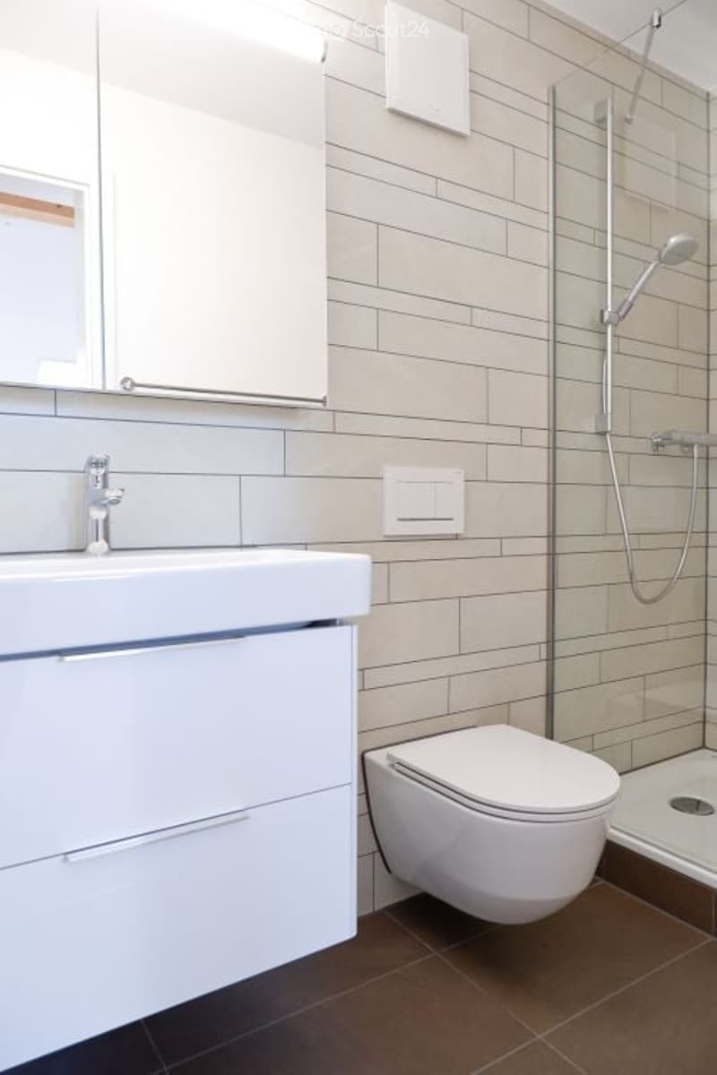 modern bathroom with white tiles, white sink, white toilet, glass shower enclosure, silver shower head