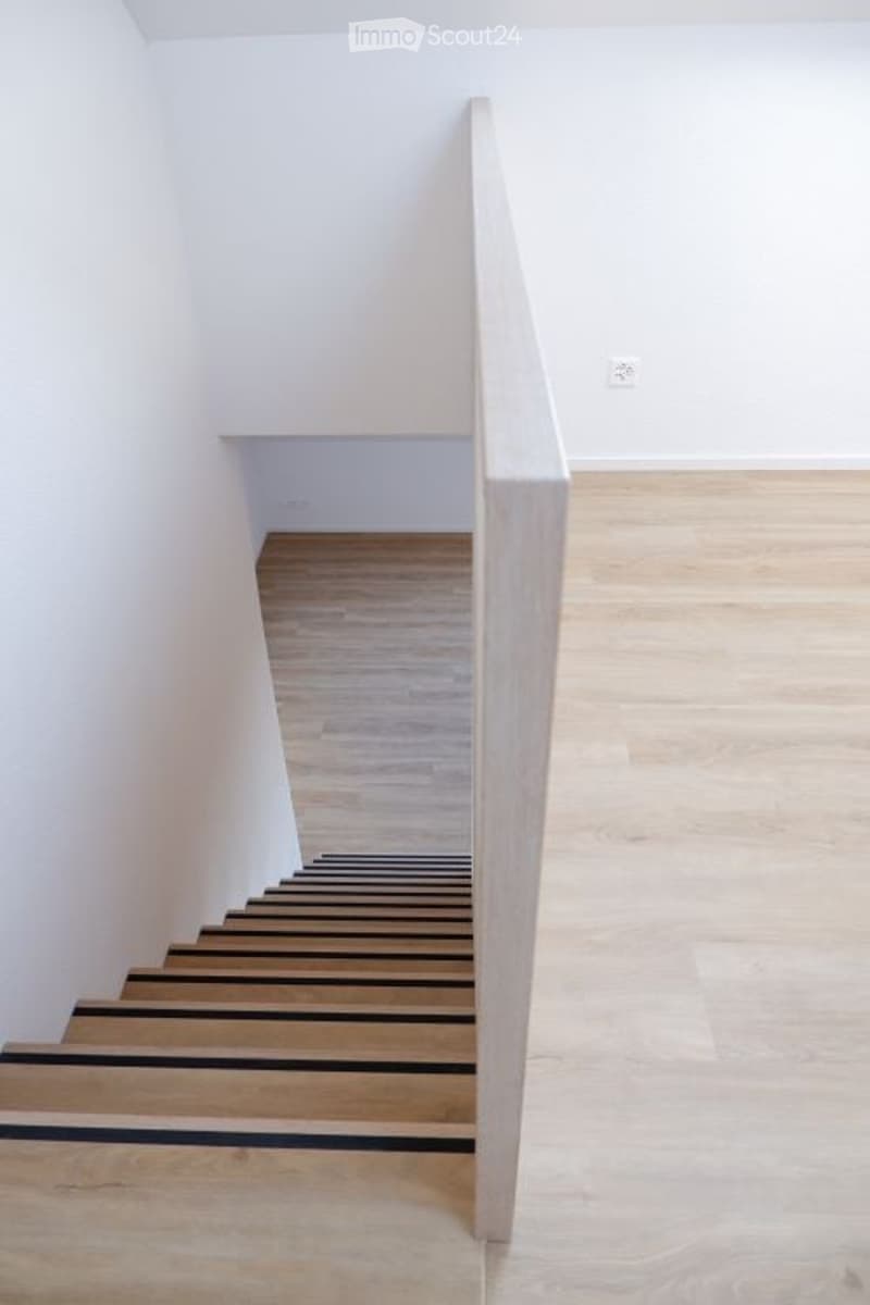 wooden staircase with black stripes, white walls, wooden floor