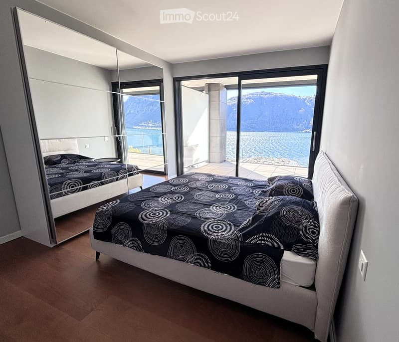 Bedroom with large bed, large mirror, balcony, sliding glass doors, lake view