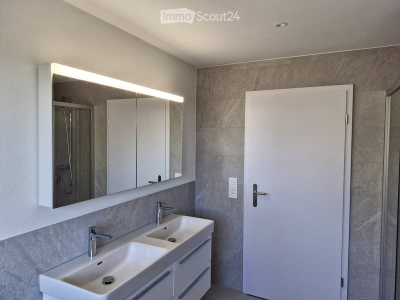 modern bathroom with double sink, mirror, shower, and white tiles