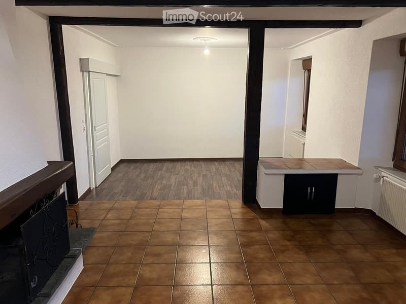 empty room, wooden floor, white walls, fireplace, white door, small window, radiator
