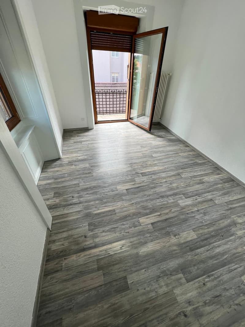 empty room, wooden floor, white walls, open door to balcony, radiator