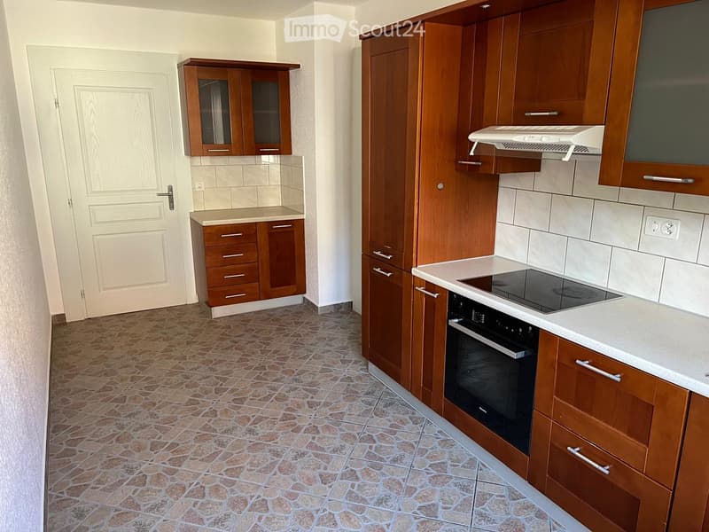 kitchen with wooden cabinets, white tiled backsplash, black stove, white countertop, power outlet