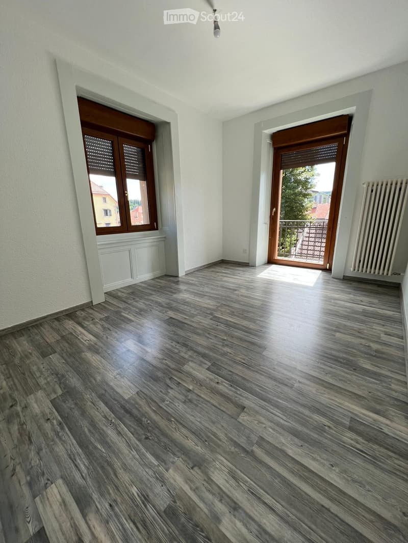empty room, wooden floor, white walls, two windows, balcony with railings