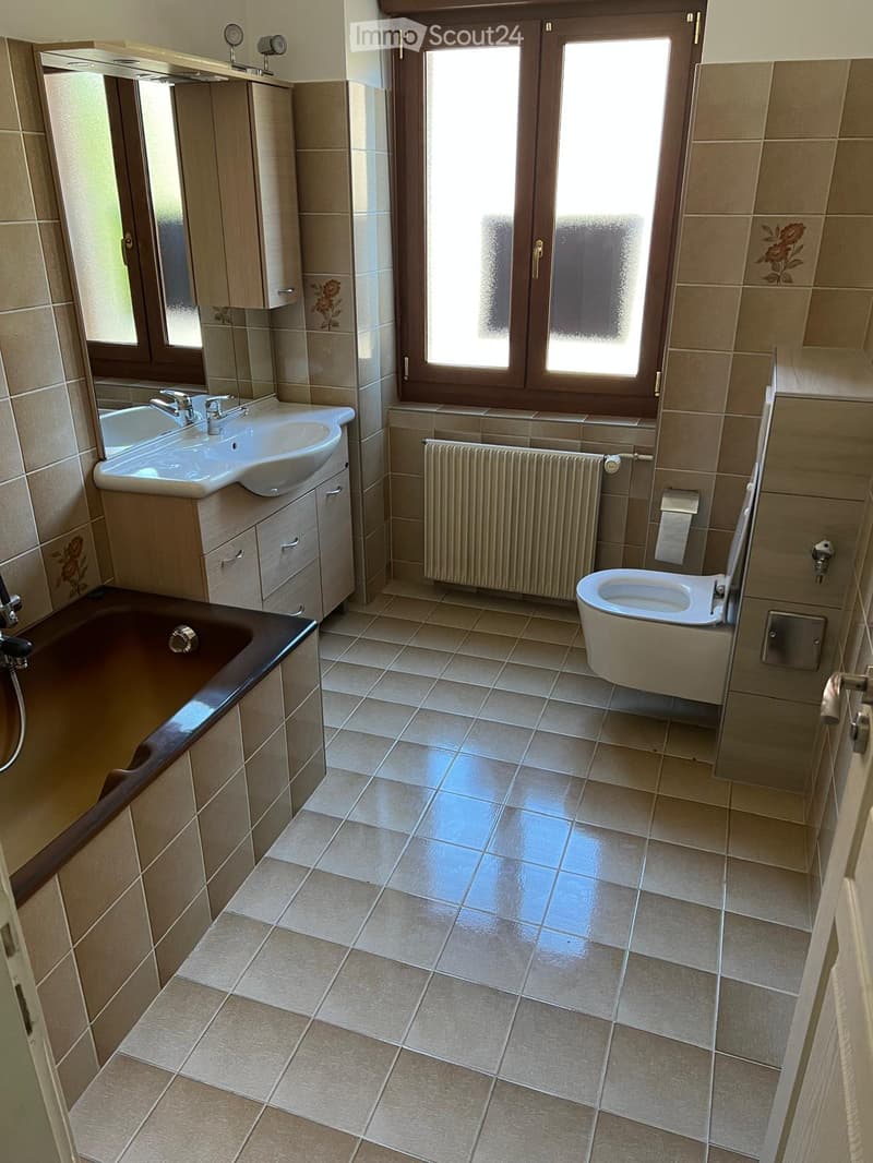 Bathroom with bathtub, sink, toilet, radiator, window, tiled floor, mirror