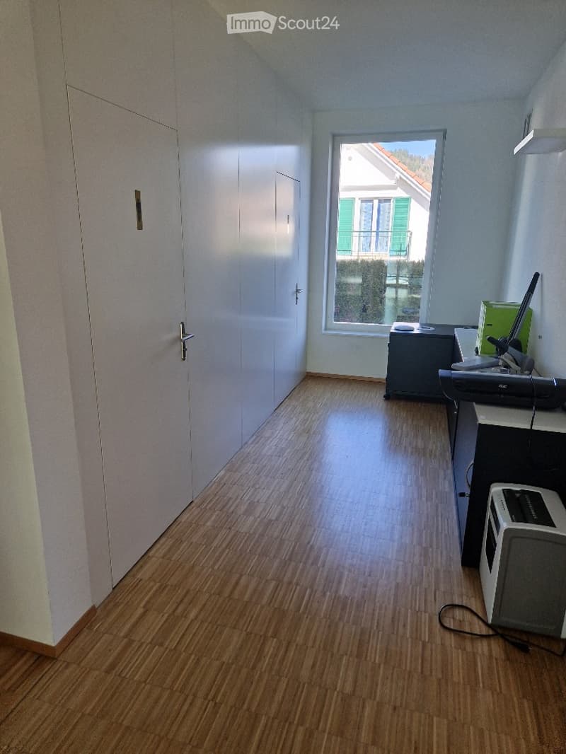 wooden floor, white walls, office desk with monitor, chair, lamp