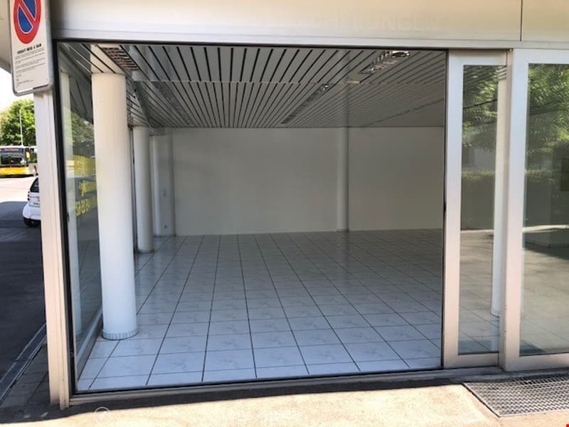 Empty garage with white tiled floor, glass doors, and pillars