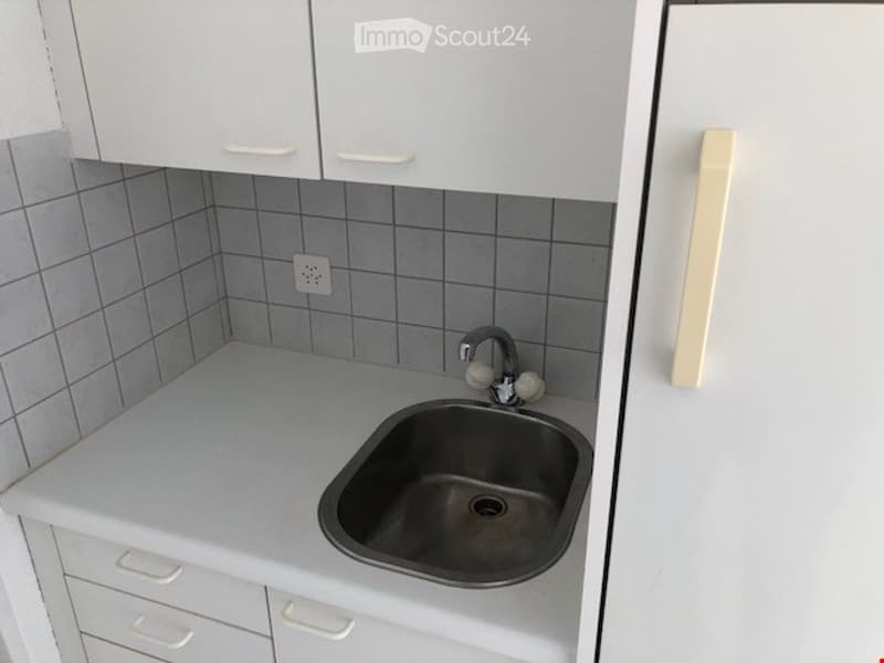 white cabinets, tiled wall, stainless steel sink, faucet, power outlet