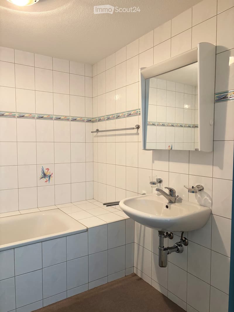 Bathroom with white tiles, bathtub, sink, mirror, towel rack, and faucet