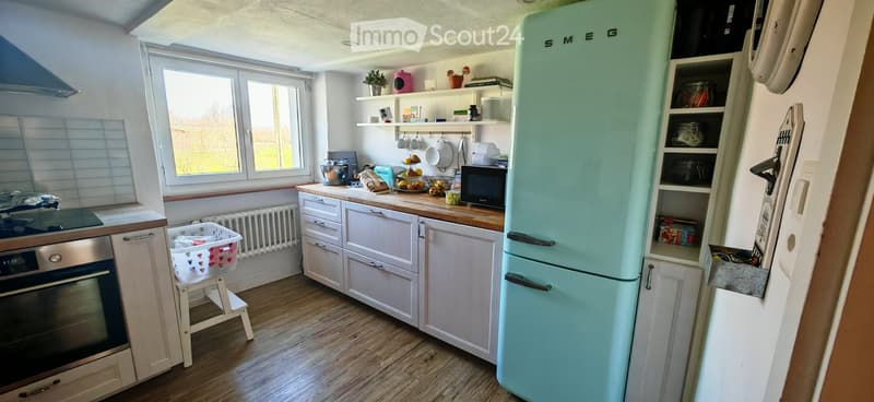 kitchen with white cabinets, wooden floor, turquoise fridge, microwave, window with view