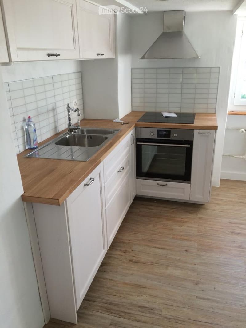 modern kitchen with white cabinets, wooden countertops, stainless steel sink, gas stove, oven, wooden floor
