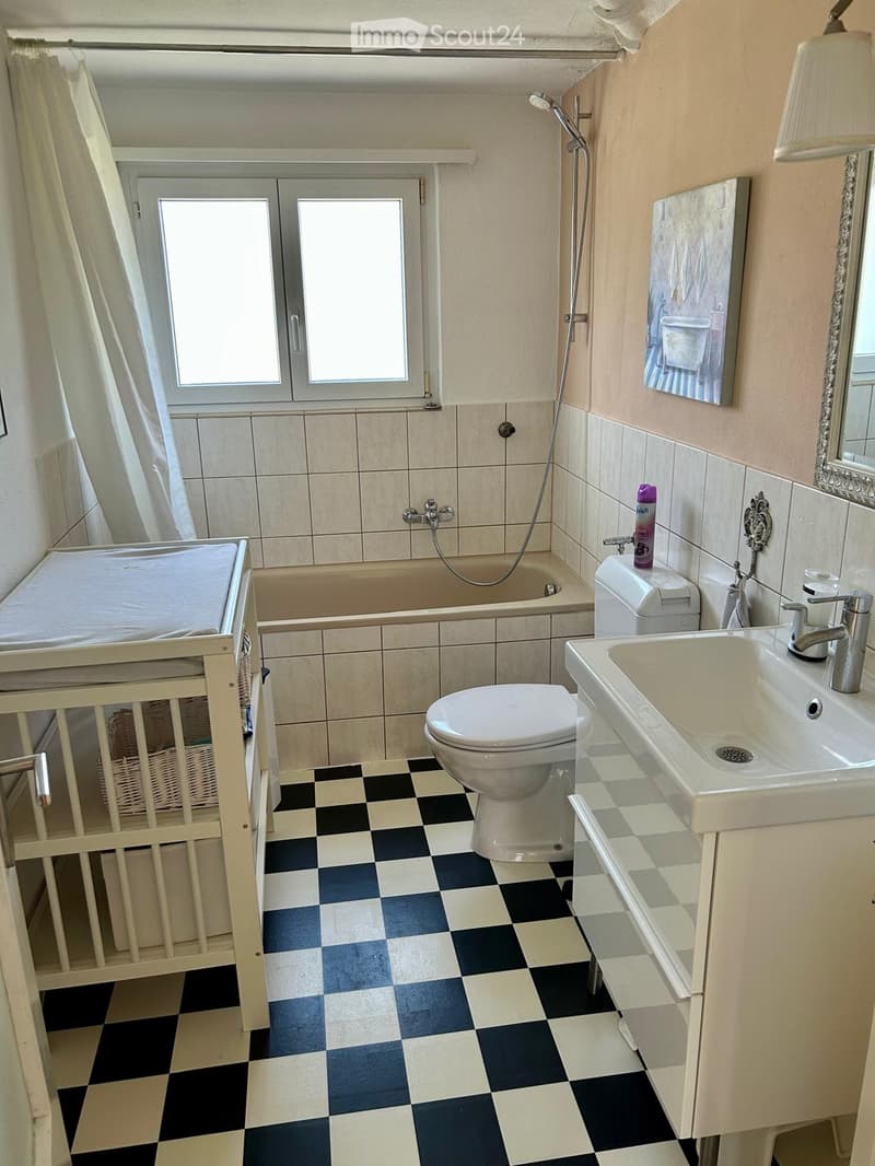Bathroom with bathtub, toilet, sink, and a baby crib. The floor is checkered black and white.