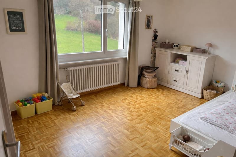 Wooden floor, white walls, large window, white bed, white cabinet, toys, radiator, basket, lamp